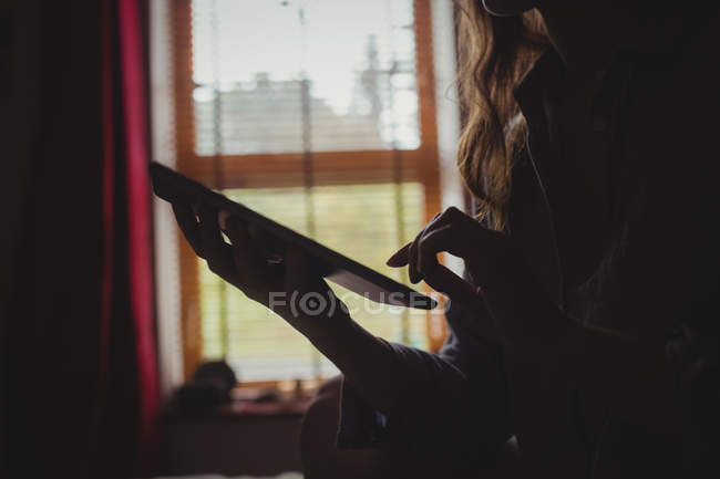 Женщина с цифровым планшетом в спальне дома — стоковое фото