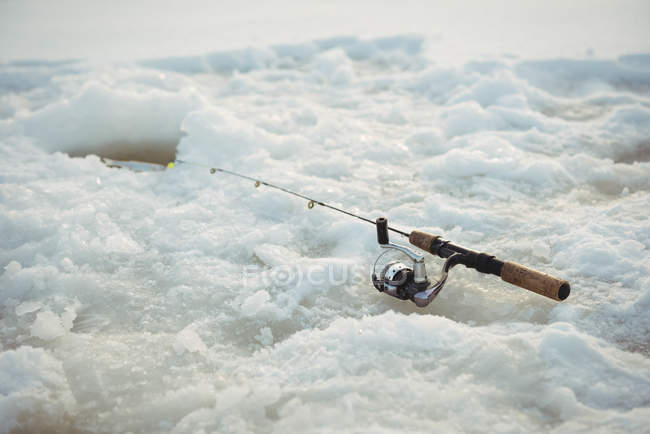 Caña de pescar alrededor del agujero de hielo en nieve - foto de stock