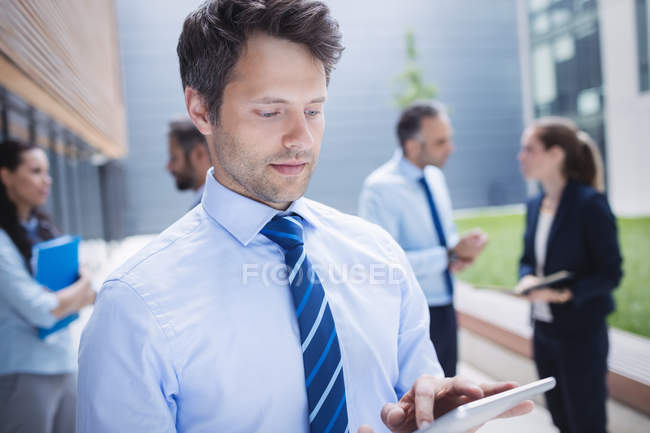 Homme d'affaires confiant utilisant une tablette numérique à l'extérieur de l'immeuble de bureaux — Photo de stock
