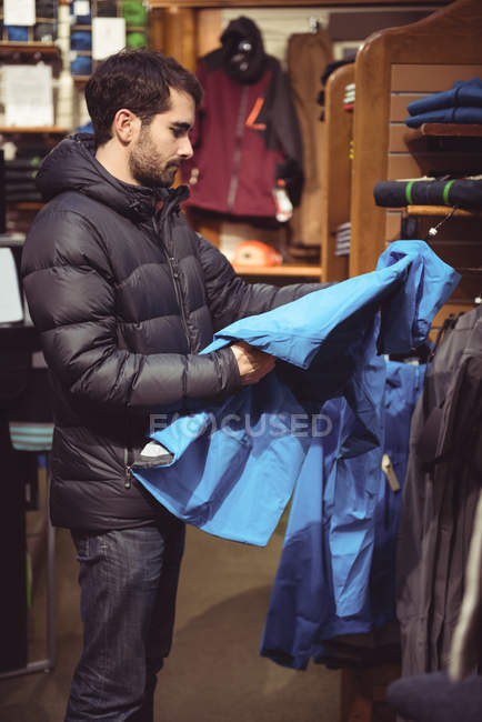 Мужчина выбирает одежду в магазине одежды — стоковое фото