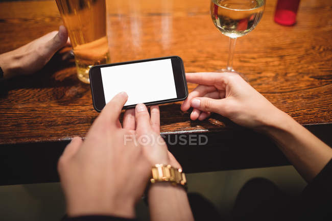 Close-up de casal usando telefone celular no balcão de bar — Fotografia de Stock