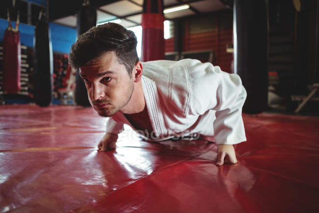 Karate player haciendo push-up en el gimnasio - foto de stock