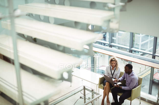 Business executives discussing over laptop at office corridor — Stock Photo