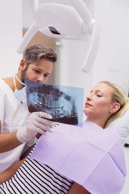 Odontoiatra che mostra i raggi X alla paziente in clinica — Foto stock