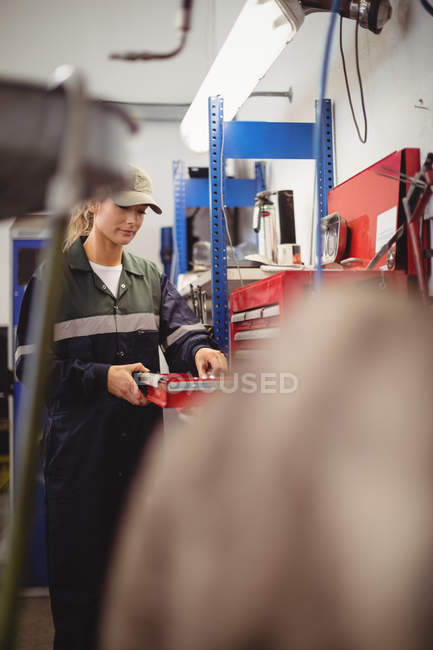 Mecânico feminino arranjar ferramentas em kit de ferramentas na garagem de reparação — Fotografia de Stock