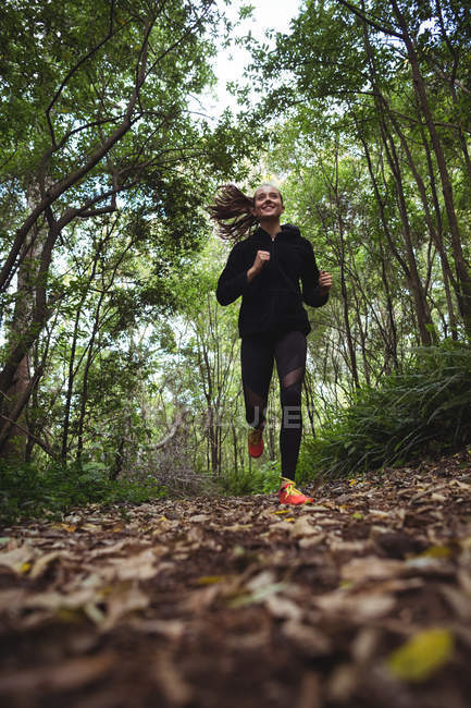 Schöne Frau joggt im Wald — Stockfoto
