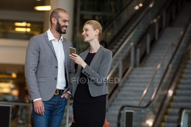 Pareja feliz usando teléfono móvil en el aeropuerto - foto de stock