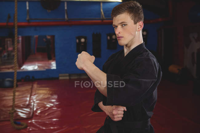 Jovem jogador de karatê adulto realizando postura de karatê no estúdio de fitness — Fotografia de Stock