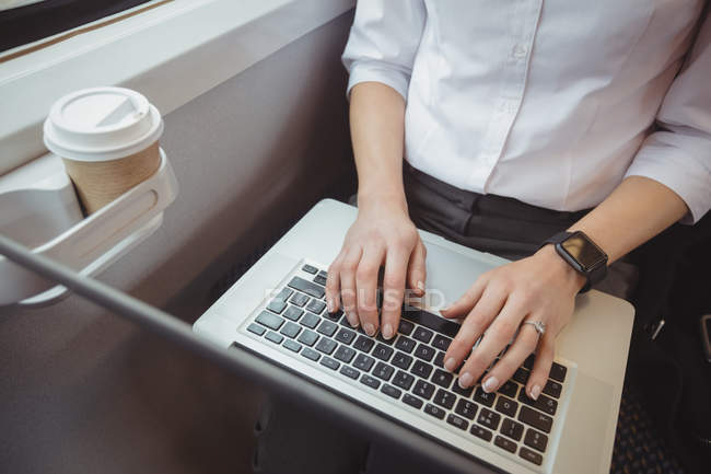 Середній розділ бізнес-леді, що використовує ноутбук під час подорожі — стокове фото