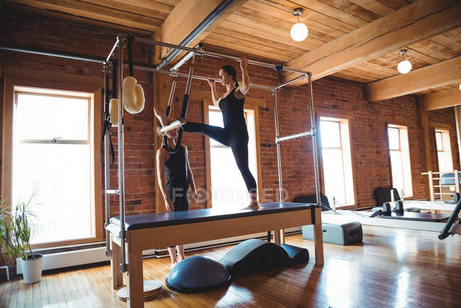 Female trainer helping woman practicing pilates in fitness studio — Stock Photo