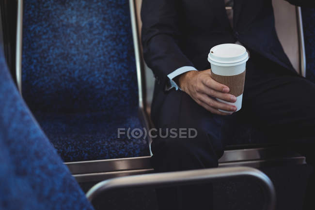 Milieu de la section de l'homme d'affaires tenant une tasse de café jetable tout en voyageant en bus — Photo de stock