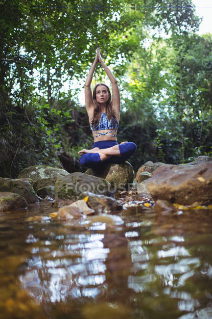 Woman meditating in lotus position in forest — Stock Photo