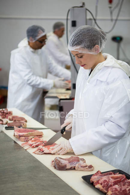Boucher femelle coupant la viande à l'usine de viande — Photo de stock