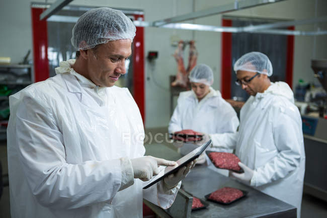 Técnicos usando tableta digital en la fábrica de carne - foto de stock