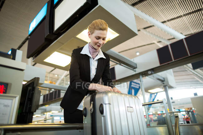 Compagnia aerea check-in attaccando etichetta al bagaglio del pendolare in aeroporto — Foto stock