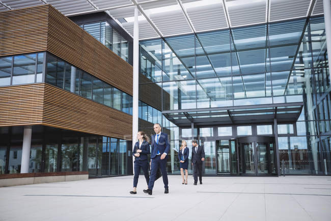 Group of business people walking outside the entrance of an office building — Stock Photo