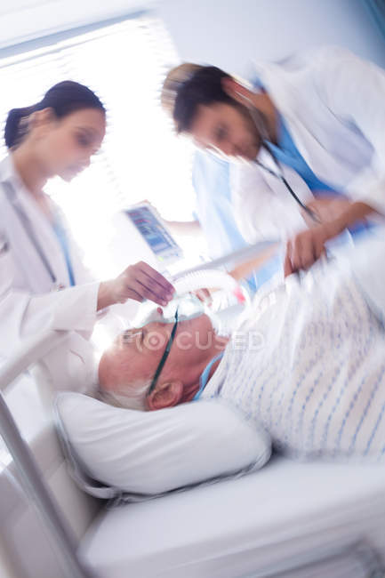 Team of doctors putting oxygen mask on patient face in the hospital — Stock Photo