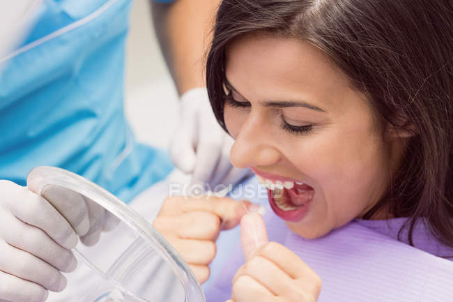 Paciente femenina que usa hilo dental en clínica dental - foto de stock