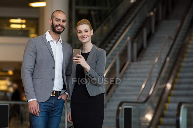 Счастливая пара с помощью мобильного телефона в аэропорту — стоковое фото