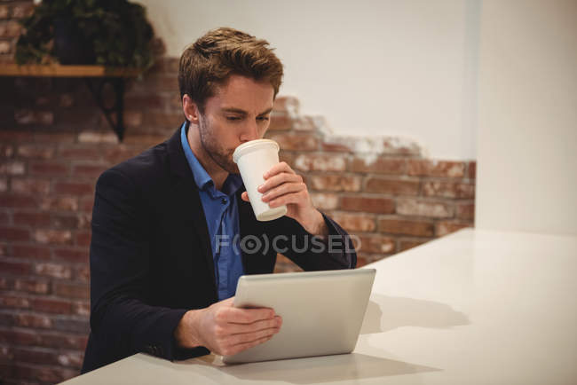 Businessman using digital tablet while having coffee in cafe — Stock Photo