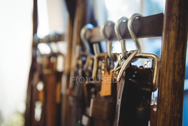 Various leather accessories hanging on hooks in workshop — Stock Photo