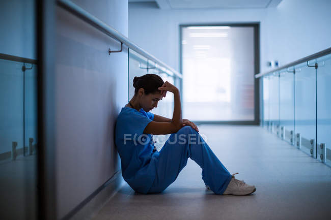Сумна медсестра сидить в коридорі в лікарні — стокове фото