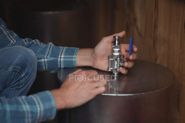 Primer plano de la válvula de fijación del hombre a mosto de cerveza para hacer cerveza en la cervecería casera - foto de stock