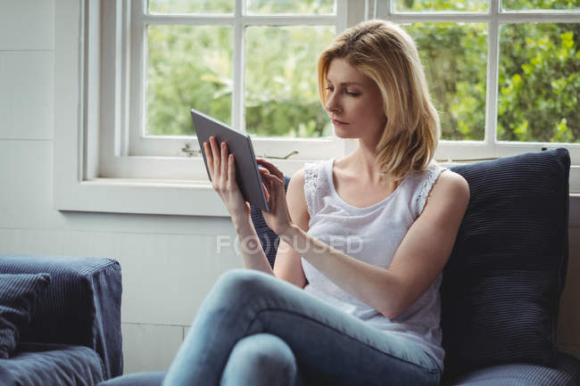 Schöne Frau mit digitalem Tablet im heimischen Wohnzimmer — Stockfoto