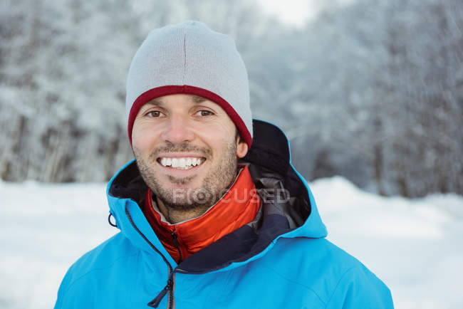 Retrato del hombre sonriente de pie sobre un paisaje nevado - foto de stock