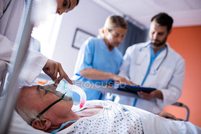 Жінка-лікар наносить кисневу маску на обличчя пацієнта в лікарні — стокове фото