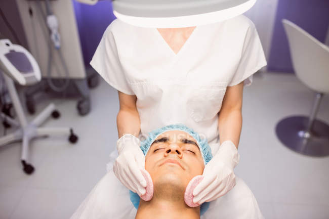 Paciente masculino que recibe masaje de médico femenino en clínica - foto de stock