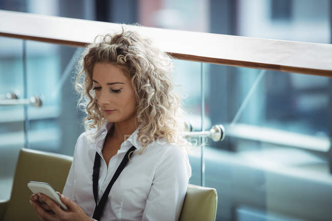 Blonde Geschäftsfrau benutzt Handy auf Büroflur — Stockfoto
