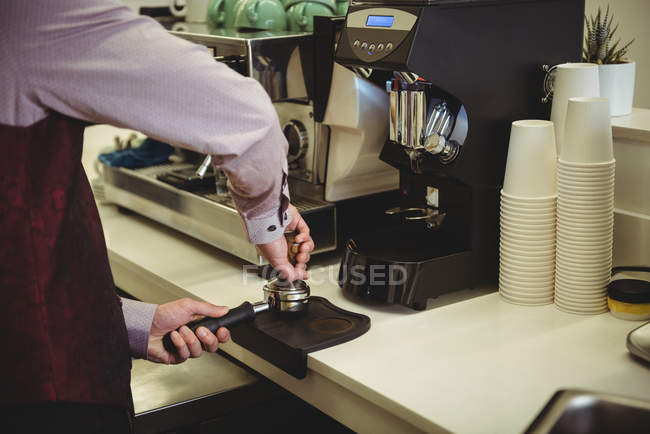 Чоловік пресує каву з тампоном у портативному фільтрі в кав'ярні — стокове фото
