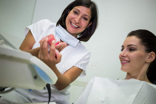 Dentista che mostra i denti modello al paziente in clinica dentale — Foto stock
