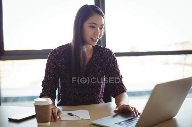 Businesswoman working on laptop in office interior — Stock Photo