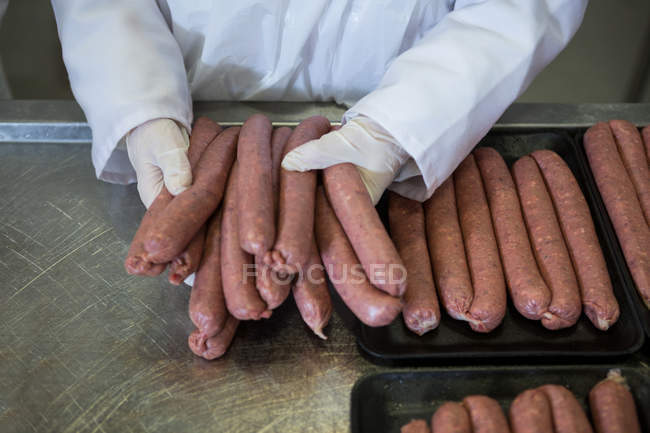 Close-up of butcher holding sausages at meat factory — Stock Photo