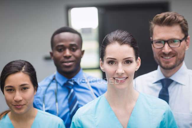 Retrato del equipo médico sonriente de pie juntos en el pasillo del hospital - foto de stock