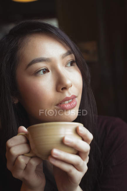 Задумчивая женщина пьет кофе в кафе — стоковое фото