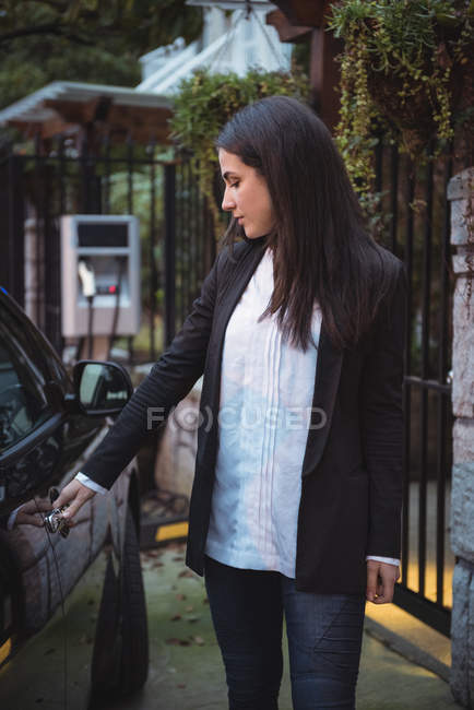 Schöne Frau öffnet Tür für Elektroautos an Ladestation für Elektrofahrzeuge — Stockfoto