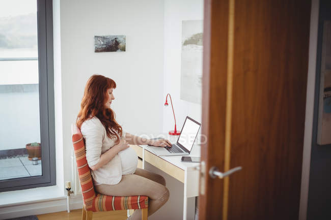 Schwangere benutzt Laptop im Arbeitszimmer zu Hause — Stockfoto