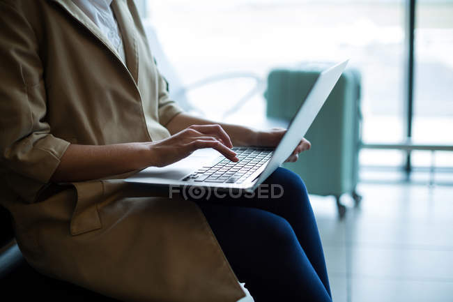 Mid section of businesswoman using over laptop at airport — Stock Photo