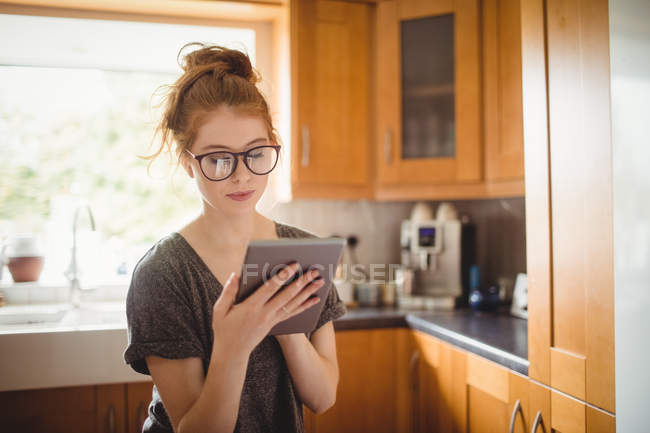 Schöne Frau mit digitalem Tablet in der Küche zu Hause — Stockfoto