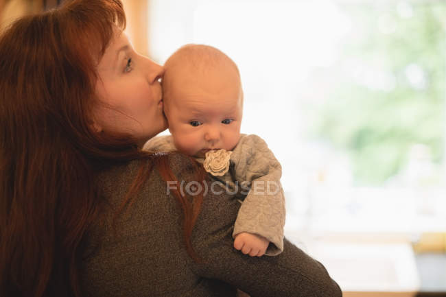 Gros plan de la mère embrassant le nouveau-né à la maison — Photo de stock