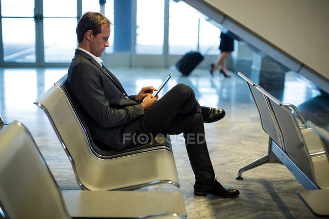 Uomo d'affari che utilizza tablet digitale nella sala d'attesa del terminal aeroportuale — Foto stock