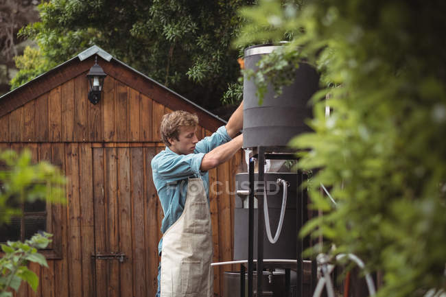 Чоловік поливає мішок з ячменю в сусло, щоб зробити пиво вдома — стокове фото