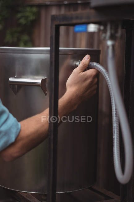 Close-up of man fixing pipe to beer wort to make beer at home brewery — Stock Photo