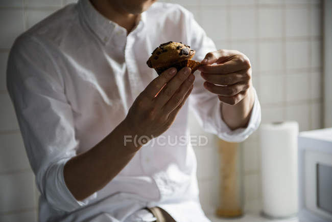 Середній розділ чоловіка, який має чашковий торт на кухні вдома — стокове фото