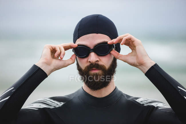 Спортсмен в гидрокостюме в плавательных очках на пляже — стоковое фото