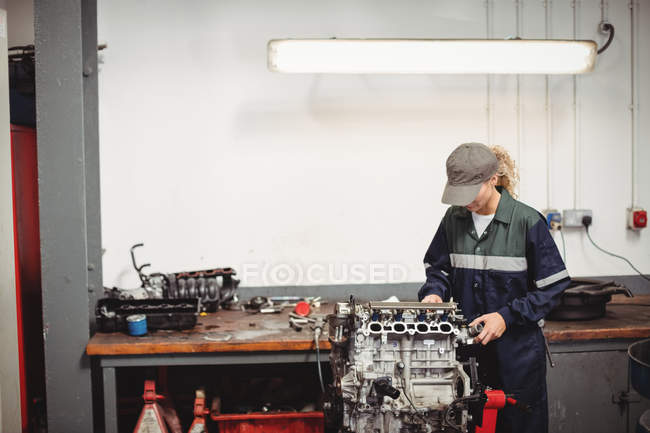 Mécanicien femelle vérifiant une voiture pièces dans garage de réparation — Photo de stock