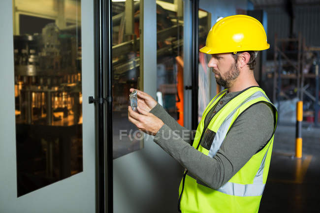 Вид сбоку на работника мужского пола, осматривающего сок в пробирке на заводе — стоковое фото